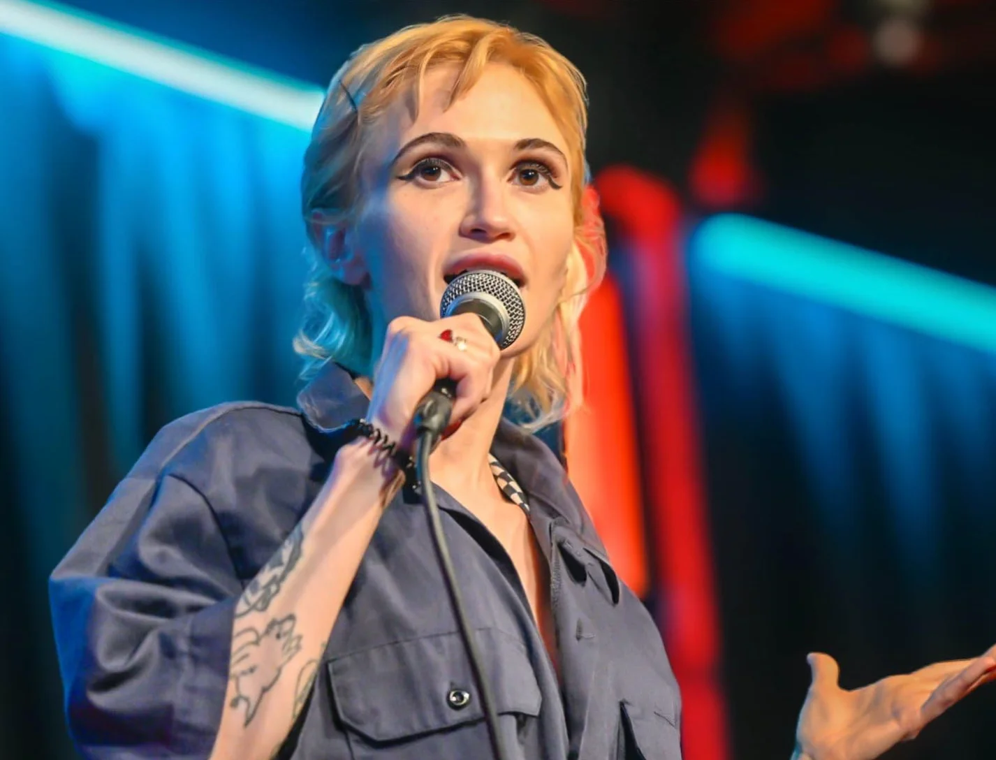 Taylor Drew holding a microphone mid-set, performing stand-up in New York City.